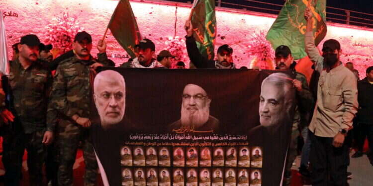 פעילי המיליציות הפרו-איראניות בעיראק מחזיקים בכרזה הנושאת את תמונותיהם של מפקד כוח קודס של משמרות המהפכה האיראני שחוסל, קאסם סולימאני, מנהיג חיזבאללה שחוסל, חסן נסראללה, וסגנו של מנהיג המיליציות שחוסל, אבו-מהדי אל-מוהנדס. צילום: EPA דאעש, כוח קודס ותקציב המיליארדים: התעצמות המיליציות הפרו-איראניות בעיראק