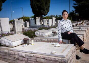 תמי שלח ליד קבר בעלה בבית העלמין תל־מונד. צילום: אריק סולטן