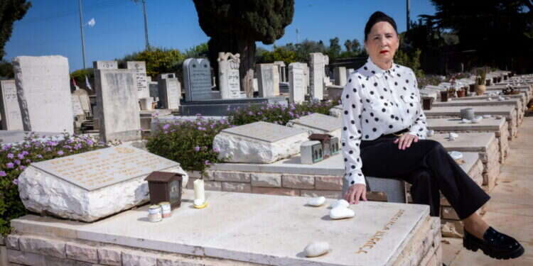 תמי שלח ליד קבר בעלה בבית העלמין תל־מונד. צילום: אריק סולטן