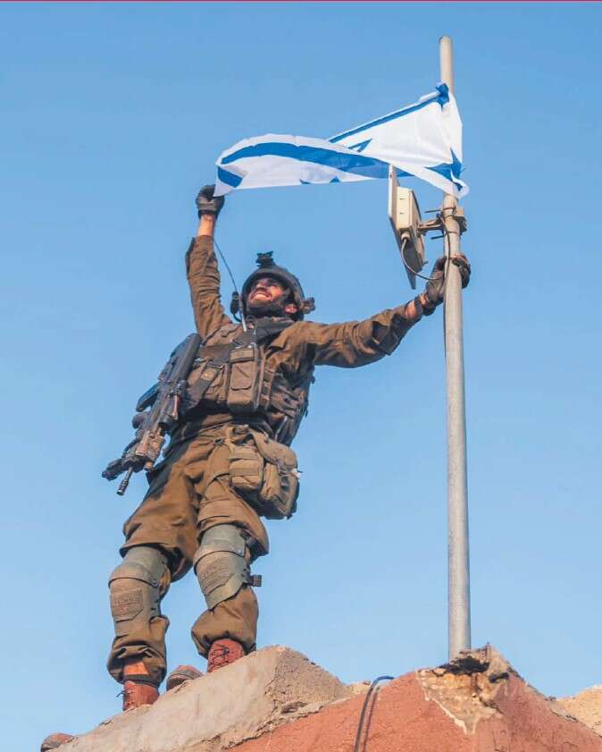 שי שמריז ז"ל מניף את הדגל על גג בית העירייה בג'בלייה. צילום: באדיבות המשפחה